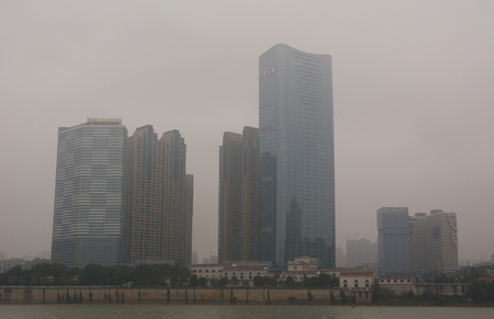 KUNMING, CHINA - NOV 10, 2015. Skyscrapers located on the river bank in mist in Kunming city, China.のeditorial素材
