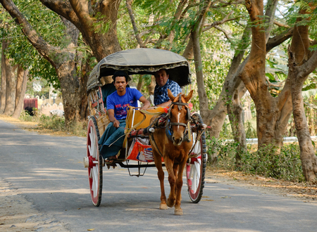 Mandalay, Myanmar - Feb 22, 2016. Horse cart carrying tourists on rural road in Mandalay, Myanmar.のeditorial素材