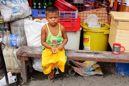 Manila, Philippines - Dec 20, 2015. A boy sitting on street at Chinatown in Manila, Philippines.のeditorial素材