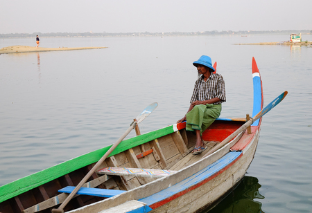 Mandalay, Myanmar - Feb 20, 2016. A man with the wooden boat on the lake in Mandalay, Myanmar.のeditorial素材