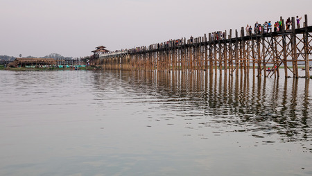 Mandalay, Myanmar - Feb 20, 2016. People walking on the Ubein bridge at sunrise in Mandalay,...