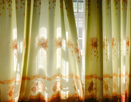Sunrise through transparent curtains of a window in the morningの写真素材