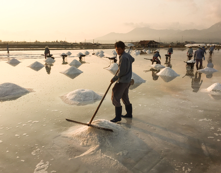 Khanh Hoa, Vietnam - Mar 21, 2016. A man working on the salt fields at sunrise in Ninh Hoa, Khanh Hoa, Vietnam. About 40 kilometers north of Nha Trang, there are immense salt fields.のeditorial素材