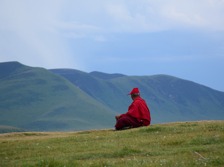 A Tibetan monk sitting on the hill in Yarchen Gar, Sichuan, China. Yarchen Gar is the largest concentration of nuns and monks in the world.の写真素材