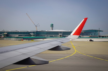 Wing of airplane with the airport background at sunny day. View from window seat.の写真素材