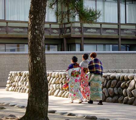 Hiroshima, Japan - Dec 28, 2015. Women in kimono walking on street in Miyajima island, Japan. Miyajima is famous for the Itsukushima Shrine, a UNESCO World Heritage Site.のeditorial素材