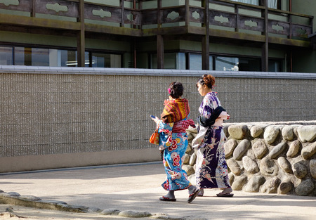 Hiroshima, Japan - Dec 28, 2015. Women in kimono walking on the road in Miyajima island, Japan. Miyajima is famous for the Itsukushima Shrine, a UNESCO World Heritage Site.のeditorial素材