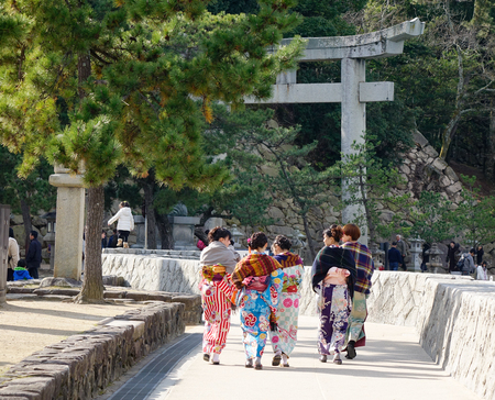 Hiroshima, Japan - Dec 28, 2015. Women in kimono walking on street in Miyajima island, Japan. Miyajima is famous for the Itsukushima Shrine, a UNESCO Site.のeditorial素材