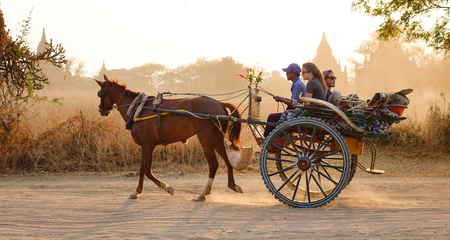 Bagan, Myanmar - Feb 19, 2016. A horse cart carrying tourists on dusty road at sunset in Bagan, Myanmar. Bagan in central Burma is one of the world's greatest archeological sites.のeditorial素材