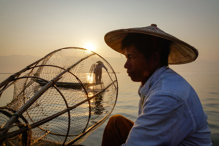 Inle, Myanmar - Feb 15, 2016. Portrait of Intha fisherman in Inle, Myanmar. He is using his unique methods of rowing and catching fish on Inle Lake at early morning.のeditorial素材