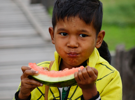 Yangon, Myanmar - Feb 26, 2016. A Burmese child eating watermelon at rural village in Yangon, Myanmar. Yangon is the country's largest city with a population of nearly 6 million.のeditorial素材