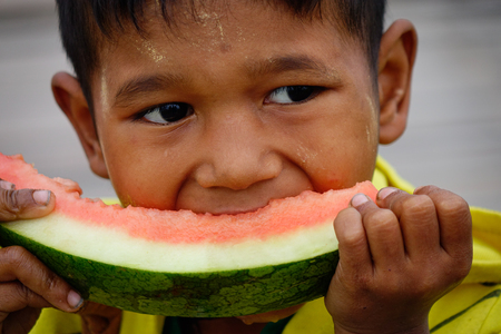 Yangon, Myanmar - Feb 26, 2016. A Burmese boy eating watermelon at rural village in Yangon, Myanmar. Yangon is the country's largest city with a population of nearly 6 million.のeditorial素材