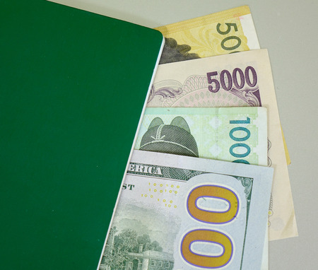 Many banknotes (US dollars, Japan yen and Korea won) with green passport - close up.の写真素材