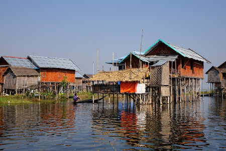 Burmese woman rowing boat at the village on Inle lake, Shan state, Myanmar. Inle Lake is a major tourist attraction, and this has led to some development of tourist infrastructure.のeditorial素材