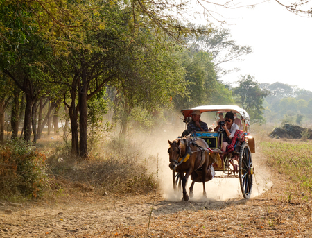 Bagan, Myanmar - Feb 18, 2016. Many horse carts carrying tourists on dusty road at sunset in Bagan, Myanmar. Bagan is an ancient city located in the Mandalay Region of Myanmar.のeditorial素材