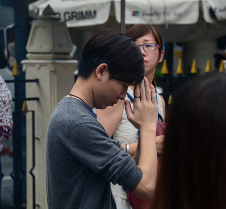BANGKOK, THAILAND - JUN 18, 2016. A young man praying at Wat Erawan in Bangkok, Thailand. Bangkok is a large city known for ornate shrines and vibrant street life.のeditorial素材