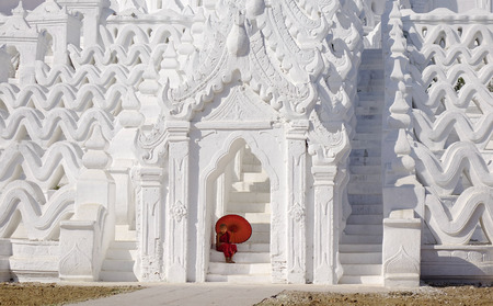 A Buddhist novice with the umbrella at the White Temple in Mandalay, Myanmar. Mandalay is Burma cultural and religious center of Buddhism.のeditorial素材