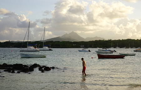 Grand Baie, Mauritius - Jan 11, 2017. A man enjoying on the beach at sunset in Grand Baie, Mauritius. Mauritius was uninhabited until 1598, and had much unique wildlife and plant life.のeditorial素材
