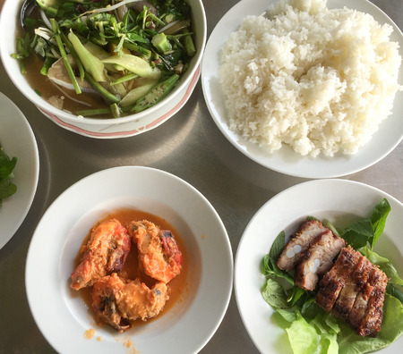 Traditional Vietnamese meal with rice, pork, seafood and vegetable.