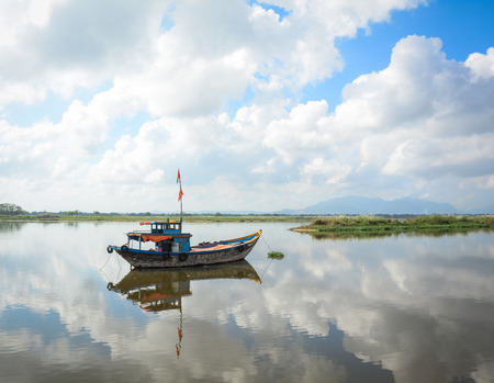 Fishing boat docking on the Hoai river at sunny day in Hoi An ancient town, Vietnam.の写真素材