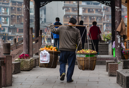 Hunan, China - Nov 6, 2015. A man selling fruits at Fenghuang Ancient Town in Hunan, China. Fenghuang is still be kept in its original appearance with 300 years passed.のeditorial素材