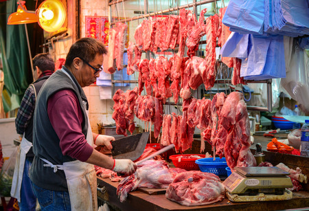 Hong Kong - Dec 30, 2014. A man selling fresh meat at local market in Hong Kong, China. Hong Kong is an important hub in East Asia with global connections to many of the world cities.のeditorial素材