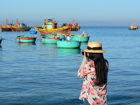 Phan Thiet, Vietnam - Mar 19, 2016. A tourist taking photographs at the fishing pier in Mui Ne town, Phan Thiet, Vietnam. Mui Ne is a coastal fishing town in the Southern Vietnam.のeditorial素材