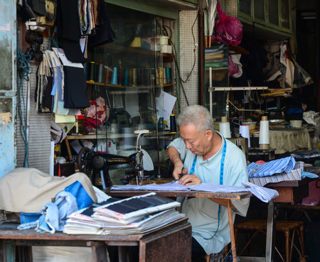 Georgetown, Malaysia - Mar 10, 2016. Street tailor with his old mechanic sewing machine at work in his small shop. This kind of job is very common in Malaysia.のeditorial素材