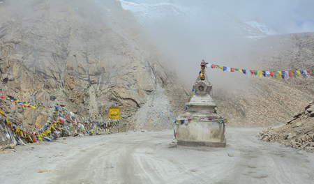 A dangerous mountain road at misty day with Tibetan stupas in Leh, Ladakh, India. Ladakh is the highest plateau in the state of Jammu & Kashmir with much of it being over 3,000 m.の写真素材