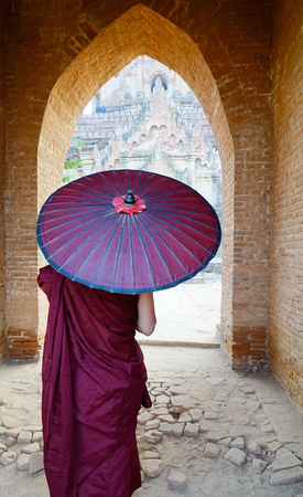 A Buddhist monk with red umbrella coming to the ancient templeの写真素材
