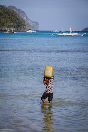 A man carrying water on the beach at sunny day in summer.のeditorial素材