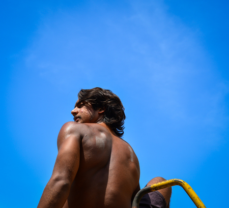 An Indian young man sitting and looking at the blue sky at sunny dayの写真素材