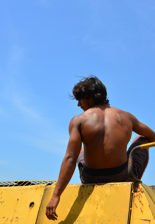 An Indian young man sitting on construction machine at sunny dayの写真素材