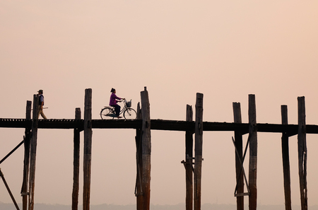 People on U Bein Bridge at sunrise in Mandalay, Myanmar. It is the world longest teak footbridge gently curves 1300yd across shallow Taungthaman Lake.のeditorial素材