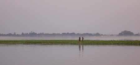 People walking on rural road with the lake at sunrise.の写真素材