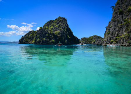 Wooden boats carry tourists on the tropical sea at blue lagoon in summer.