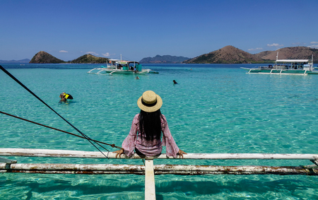 Palawan, Philippines - Apr 11, 2017. A woman sitting on wooden boat at sunny day in Palawan, Philippines. The Palawan coast is one of the most unspoilt places in the world.のeditorial素材