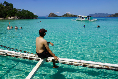 Palawan, Philippines - Apr 11, 2017. A tourist sitting on wooden boat at sunny day in Palawan, Philippines. The Palawan coast is one of the most unspoilt places in the world.のeditorial素材