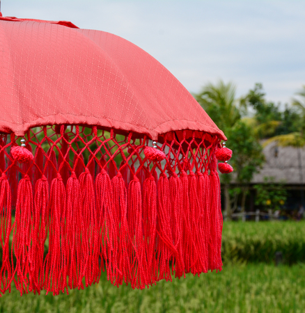 Balinese red umbrella on the rice field in Bali, Indonesia. Close up.の写真素材