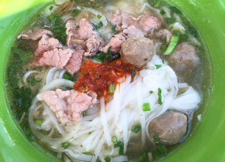 Bowl of Vietnamese pho noodle soup with rare beef, tendon, tripe and brisket served with onions,...