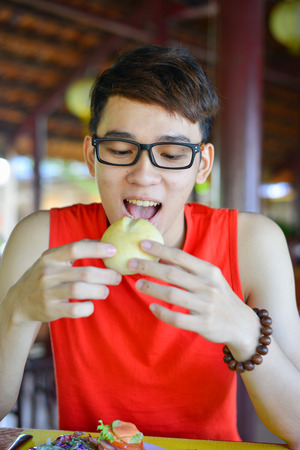 Asian man eating bread for breakfast at local restaurant in Vietnam.の写真素材