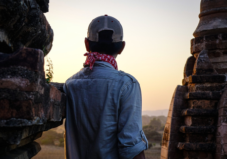 A tourist standing on a Buddhist temple in Bagan, Myanmar. Bagan is an ancient city that was the capital of the first Burmese empire.の写真素材