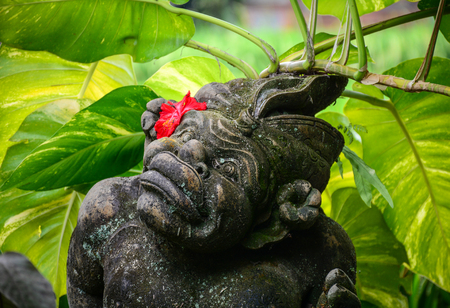 A God statue with red flower for decorations at the ancient Hindu temple in Bali, Indonesia.の写真素材