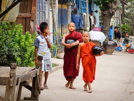 Mandalay, Myanmar - Feb 25, 2016. Buddhist monks walk on rural road in Mandalay, Myanmar. Mandalay...