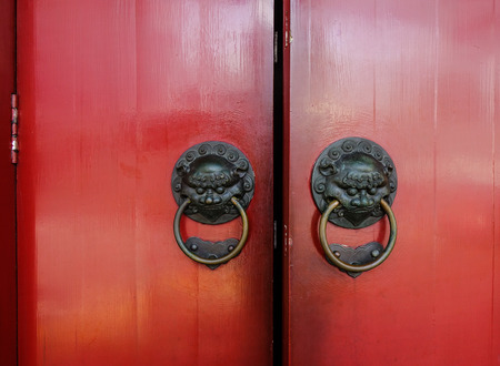 Old bronze knocker with red door in Chinese temple.の写真素材