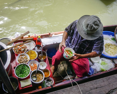 Bangkok, Thailand - Jun 19, 2017. Vendor cooking on boat at Damnoen Saduak floating market in...