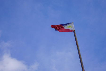 Flag of Philippines raised up in the blue sky at sunny day.