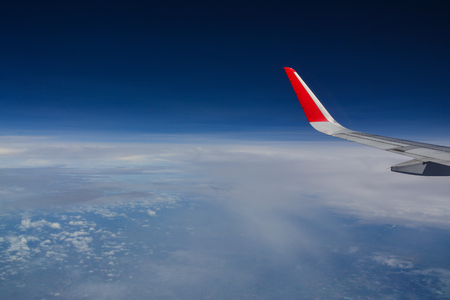 Looking through window aircraft during flight. Flying over the blue sky.の写真素材