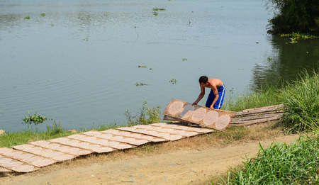 Mekong Delta, Vietnam - Mar 23, 2016. Drying rice paper wrappers on riverbank in Mekong Delta, Vietnam. Life in the Mekong Delta revolves much around the river.のeditorial素材