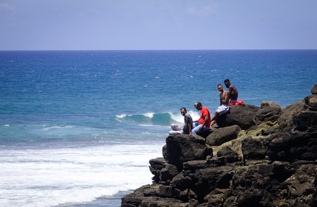 Le Morne, Mauritius - Jan 8, 2017. People sitting on rocks at south coast of Mauritius Island. Mauritius enjoys a tropical climate with clear warm sea waters, beaches, tropical fauna.のeditorial素材